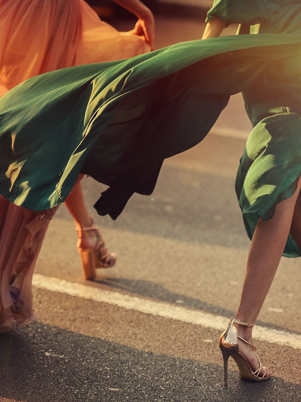 Trois femmes en robes longues traversent la rue en chaussures hautes