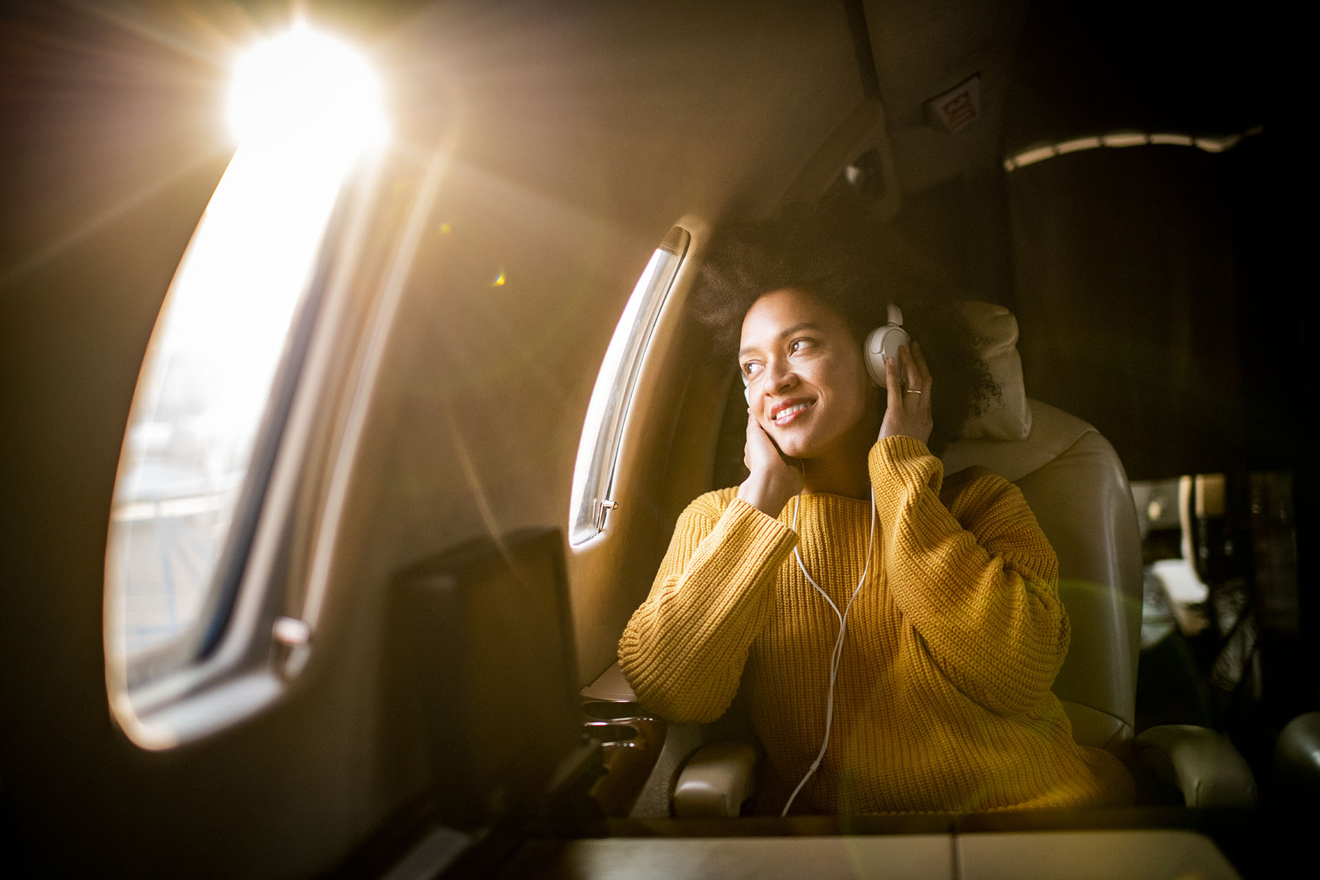 Mujer sentada en un avión escuchando música con auriculares