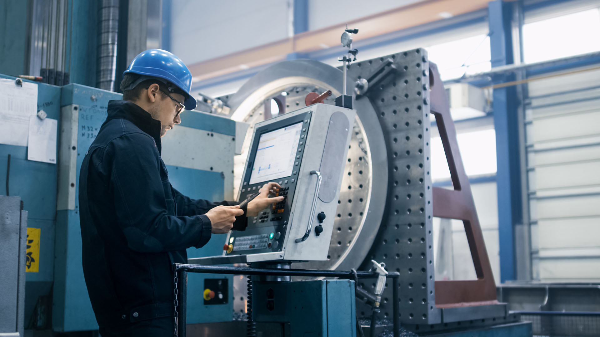 Man with blue safety helmet checks a machine