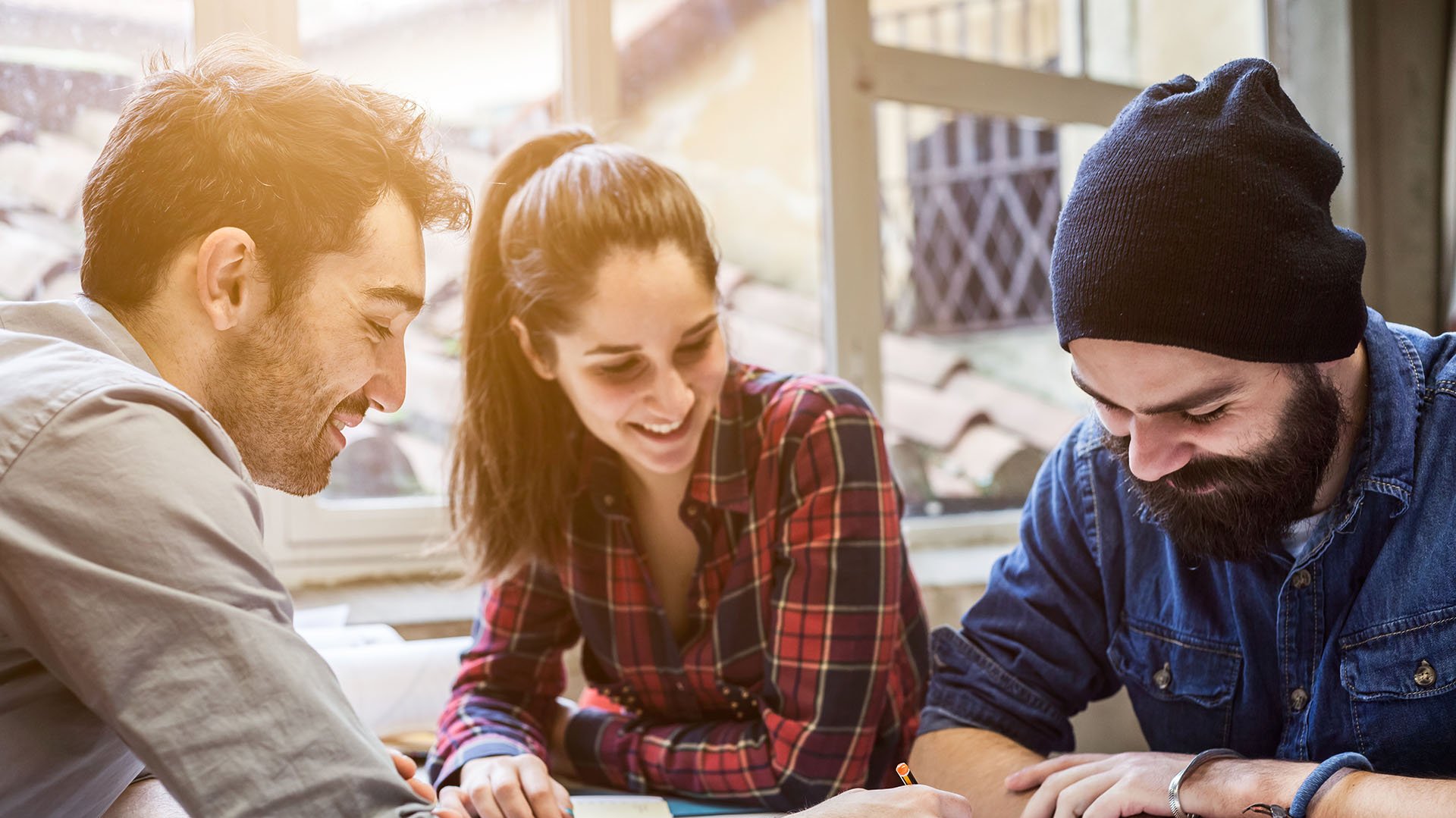 Drei Studenten arbeiten gemeinsam und lachen