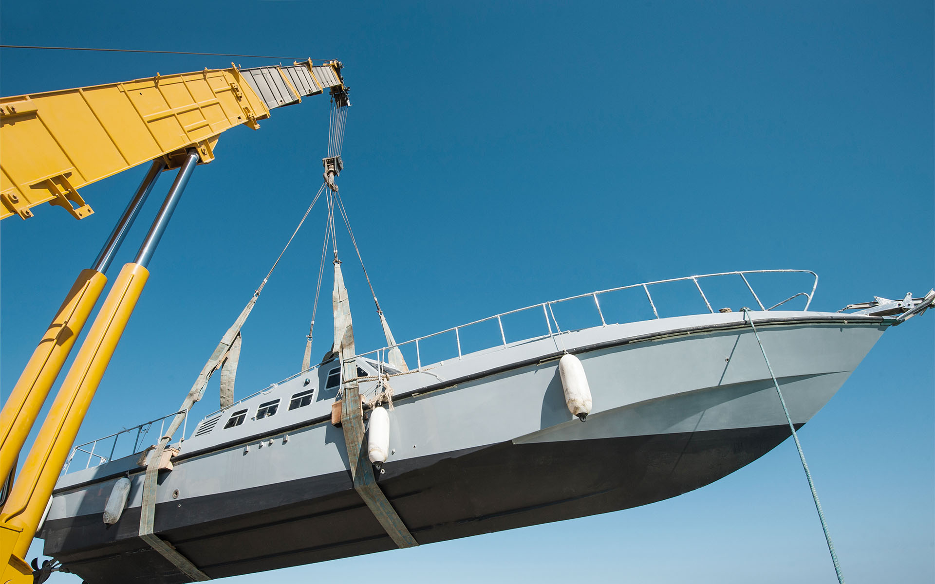Yellow telescopic crane lifts a ship