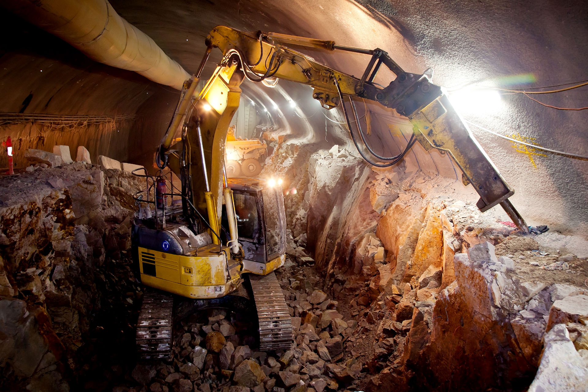 Excavadora amarilla con martillo neumático en un túnel