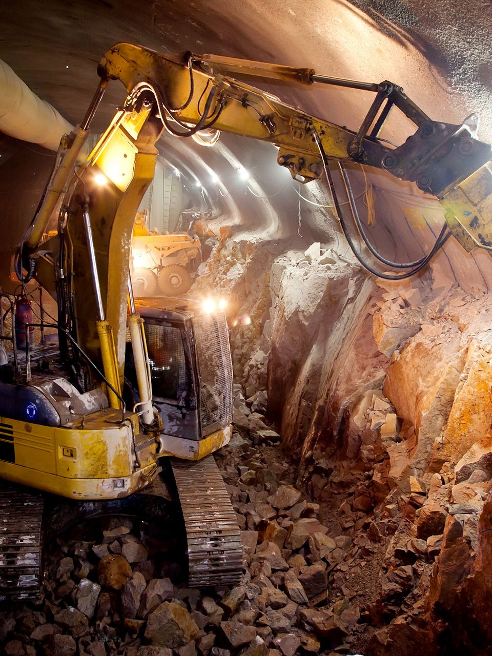 Excavadora amarilla con martillo neumático en un túnel