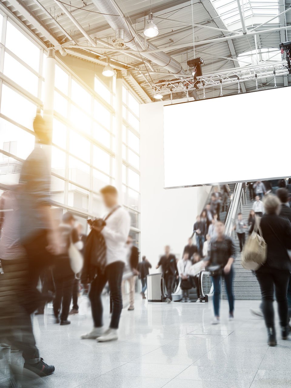 Des gens marchent dans un grand hall et prennent des escalators