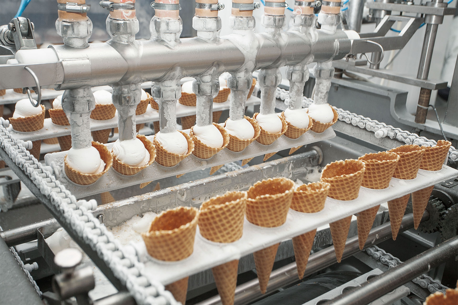 Waffle cones are filled with ice cream in a machine