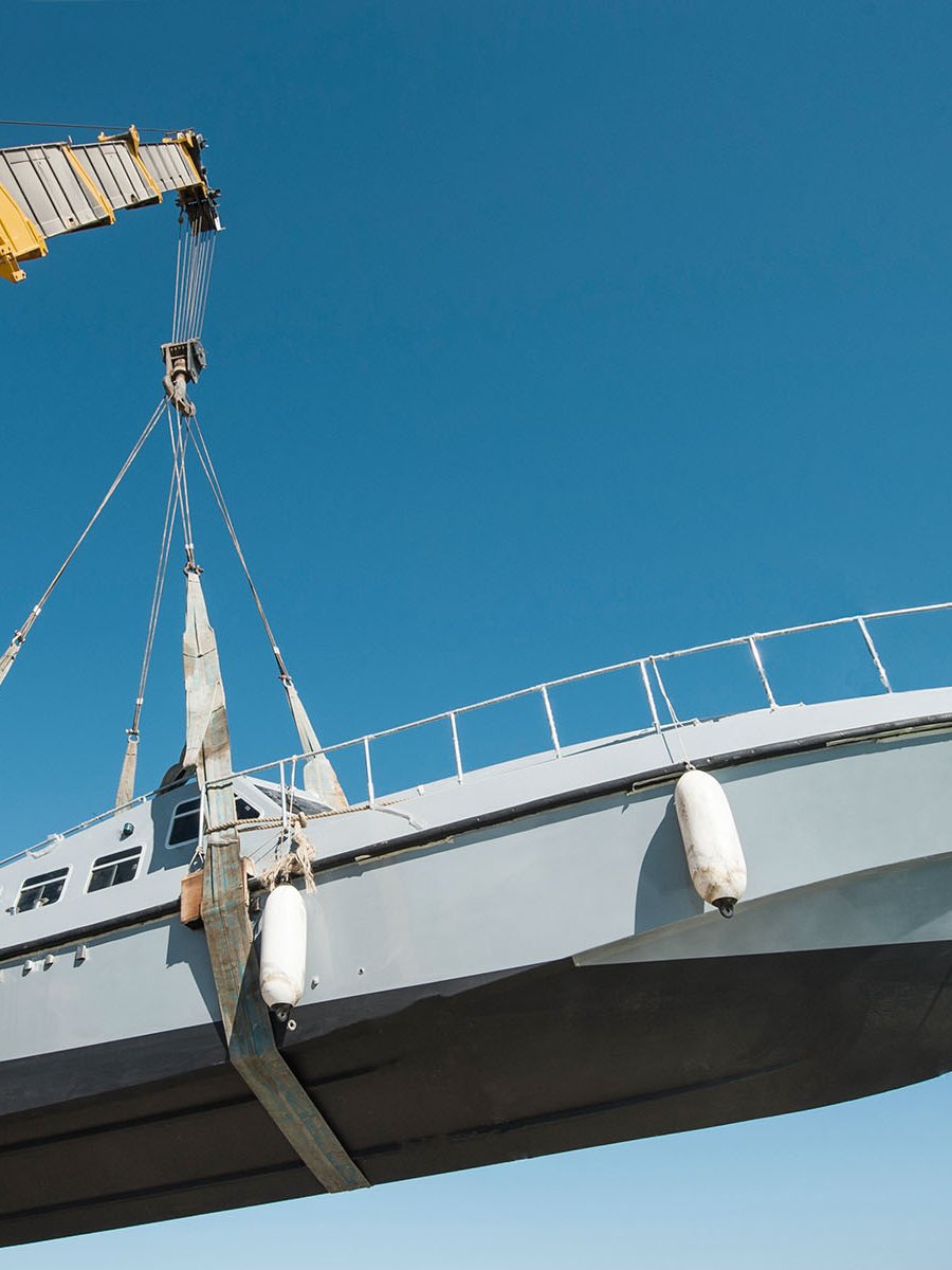 Une grue télescopique jaune soulève un navire