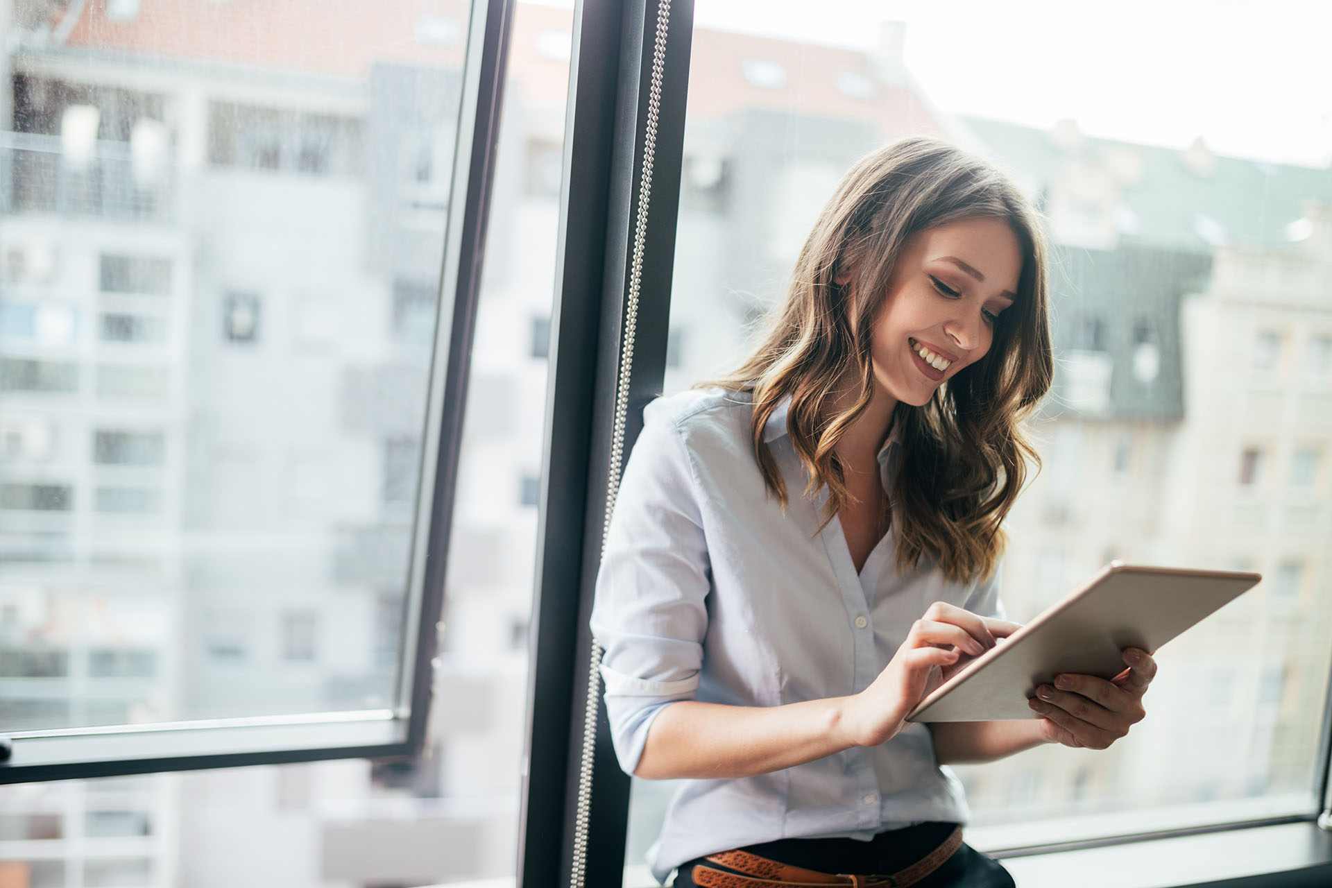 Femme assise devant une fenêtre et regardant sa tablette