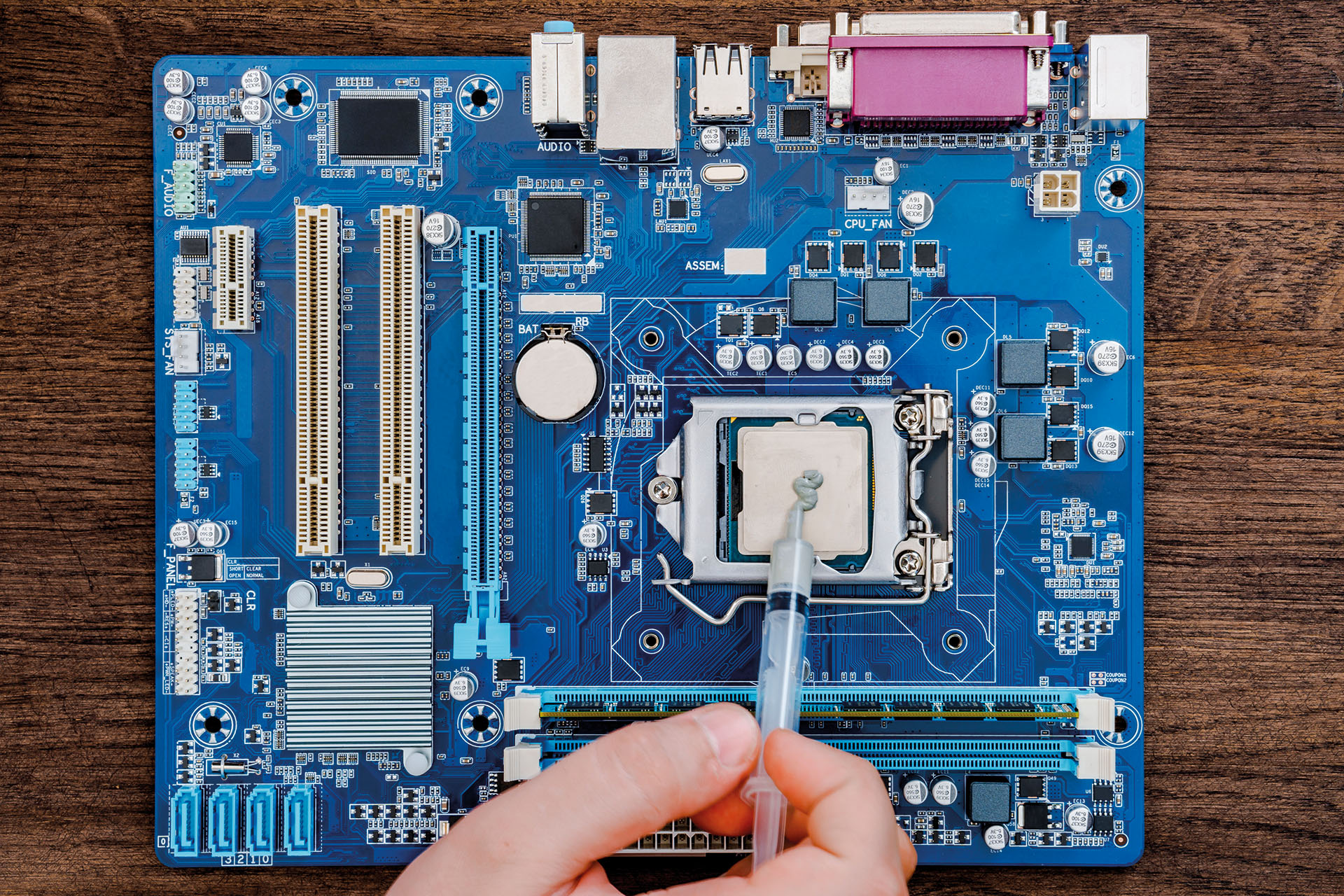 Thermal paste is applied to the CPU socket of a motherboard